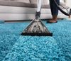 A woman is cleaning a carpet with a vacuum cleaner.