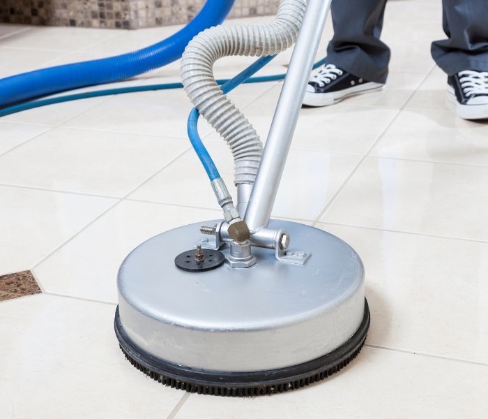A person is cleaning a tile floor with a vacuum cleaner.