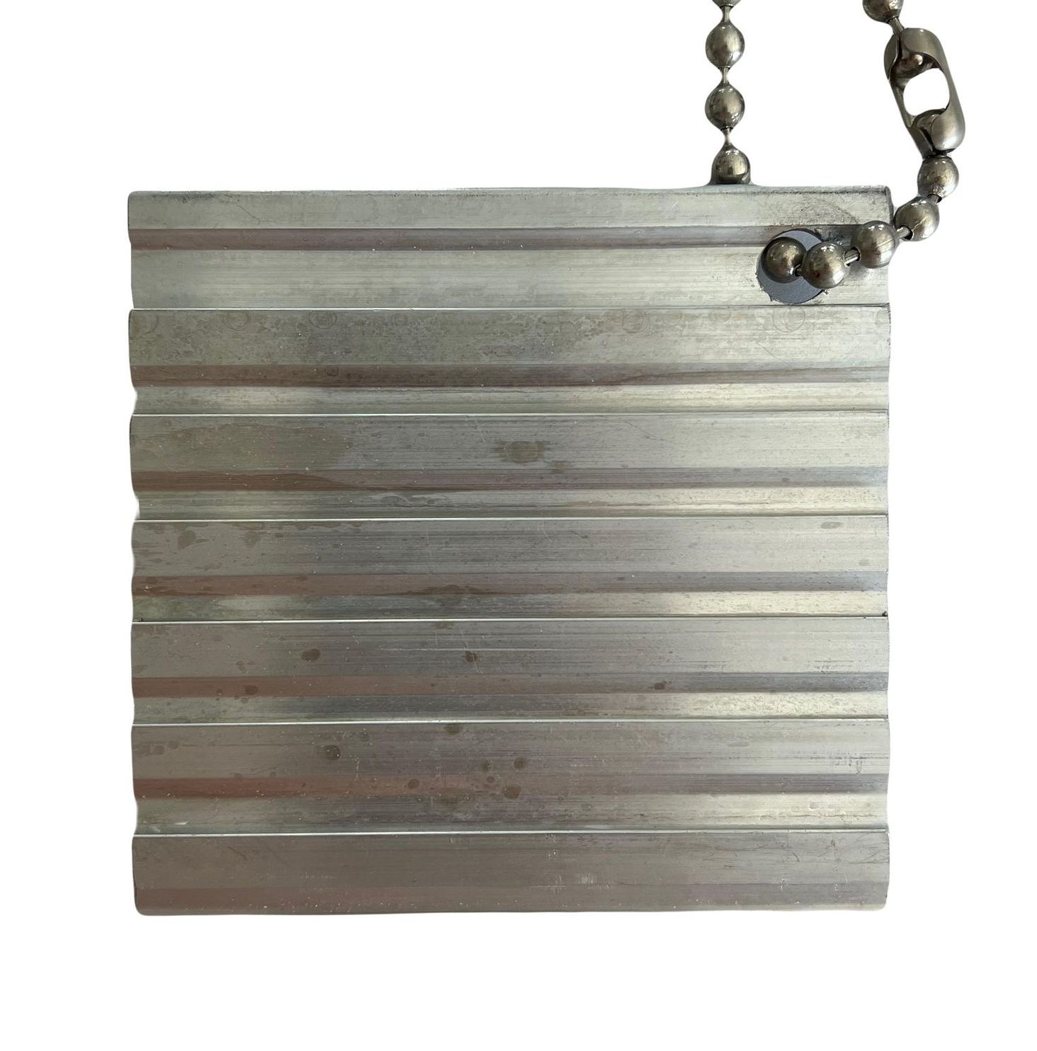 A piece of metal hanging from a chain on a white background