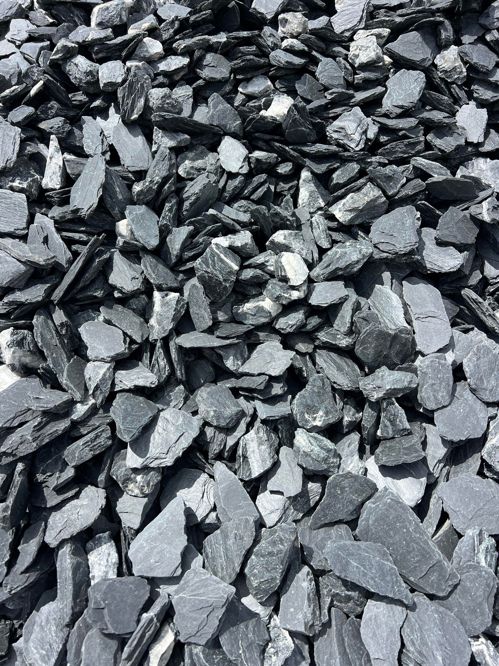 A pile of black slate chips is sitting on the ground.