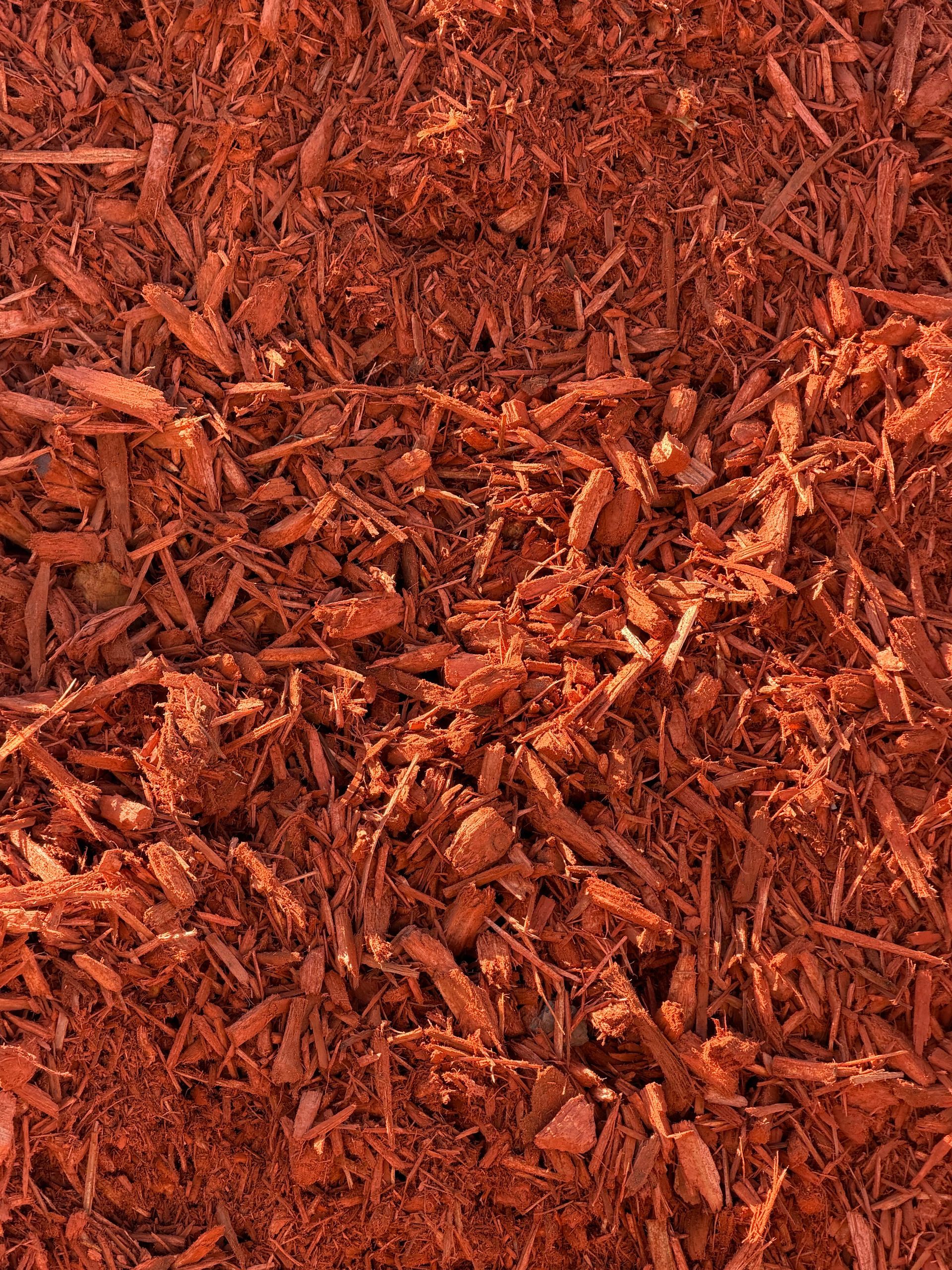 A pile of red mulch is sitting on the ground.