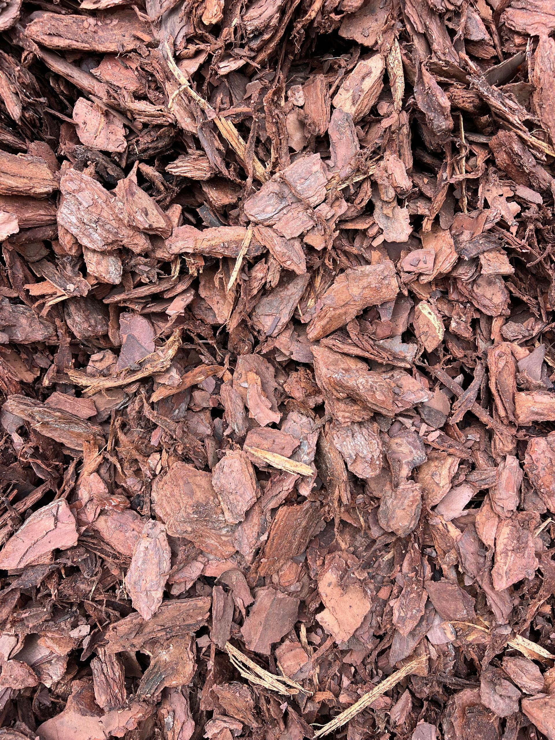 A pile of brown bark is sitting on the ground.