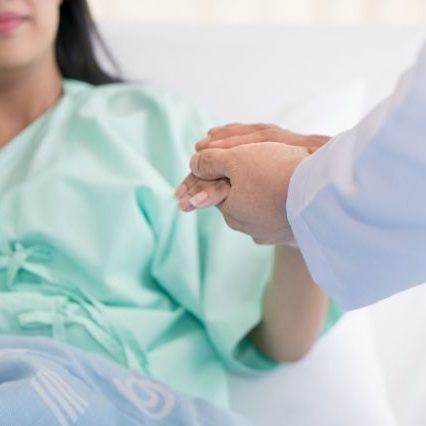 Friendly man doctor hands holding patient hand sitting at the desk for encouragement, empathy, cheering and support while medical examination. Bad news lessening, trust and ethics concept