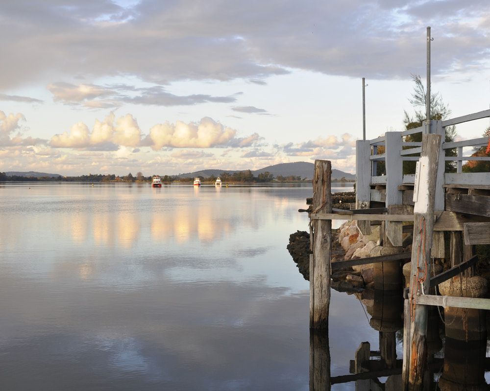 A Dock Overlooking a Body of Water with Mountains in The Background — Illawarra Sign Group in Nowra, NSW
