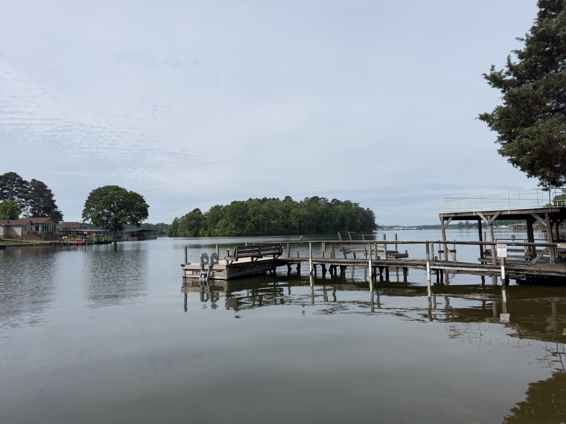 Calm waterfront with wooden docks, still water, distant trees, and a cloudy sky
