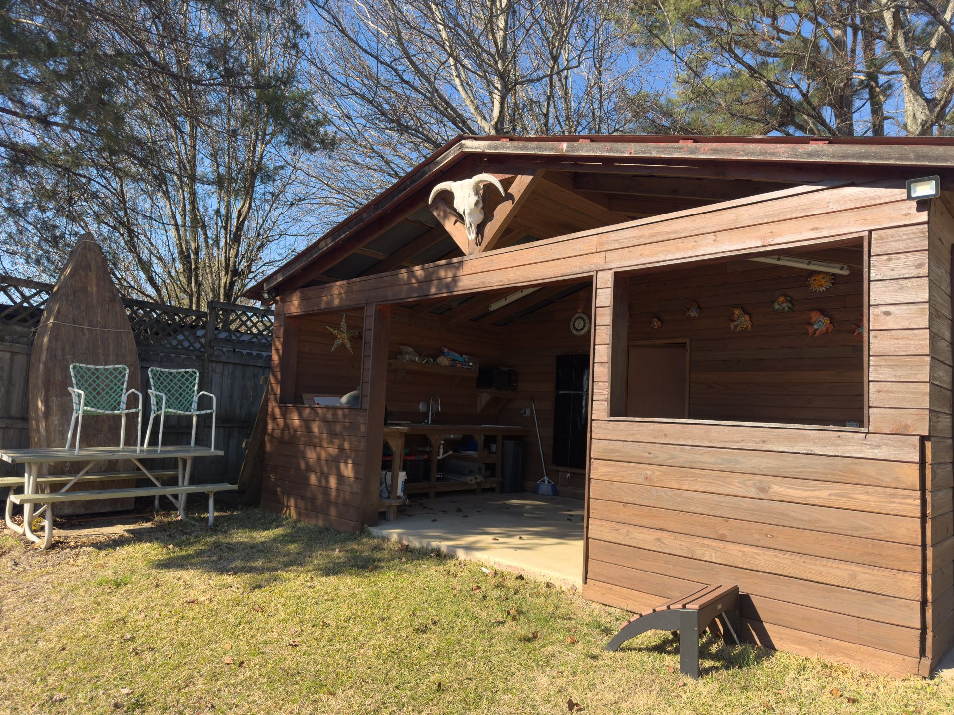 Wooden outdoor covered patio with picnic table and chairs.
