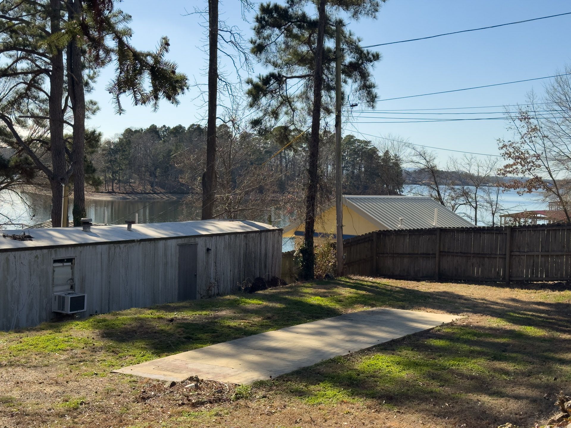 A lakeside view with trees, a building, and a concrete path.