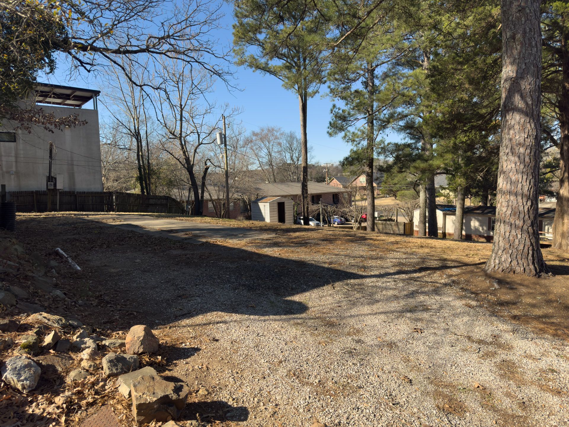 Gravel driveway leading to homes with trees on a sunny day.