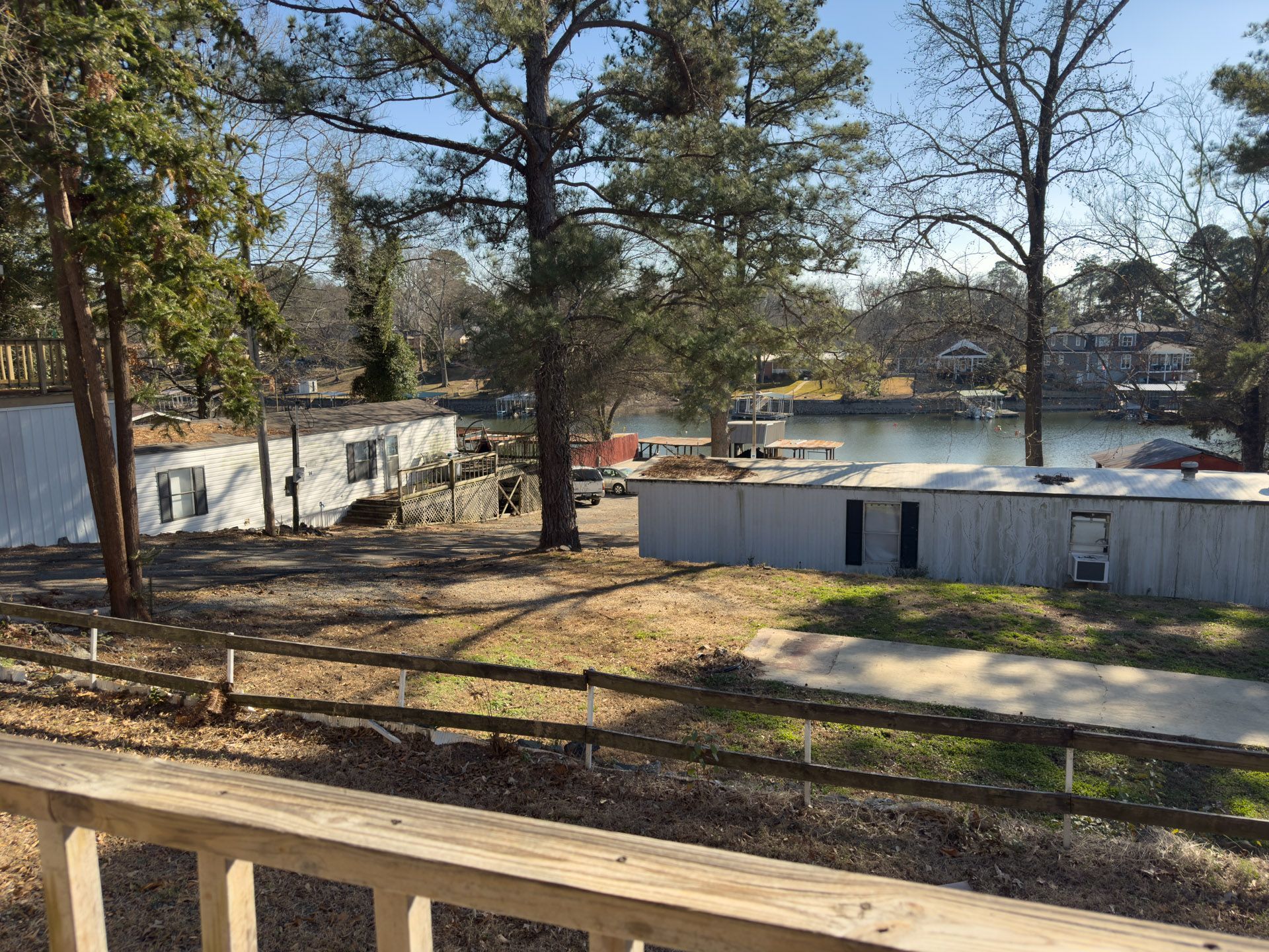 Buildings near water with trees and a wooden fence in the foreground.