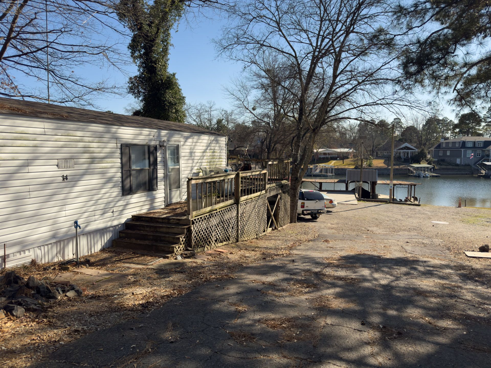 Mobile home with a deck overlooking a lake and dock.