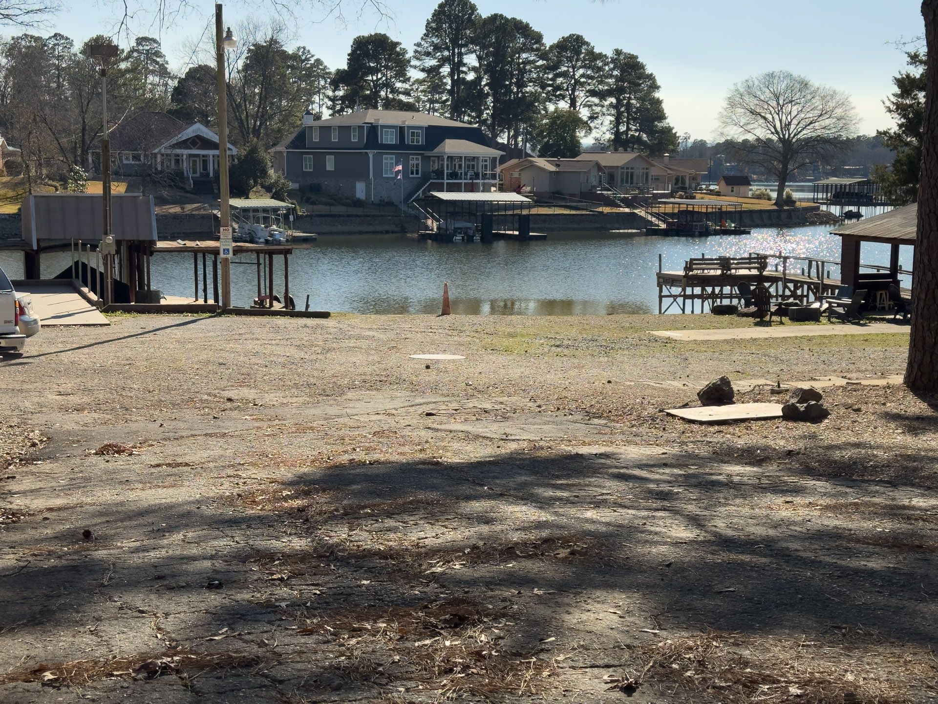 Waterfront with houses, docks, and a gravel area in the foreground.