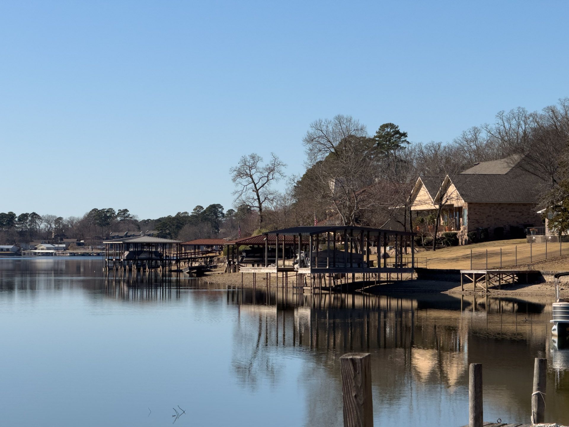 Calm lake reflecting docks and houses on a sunny day.