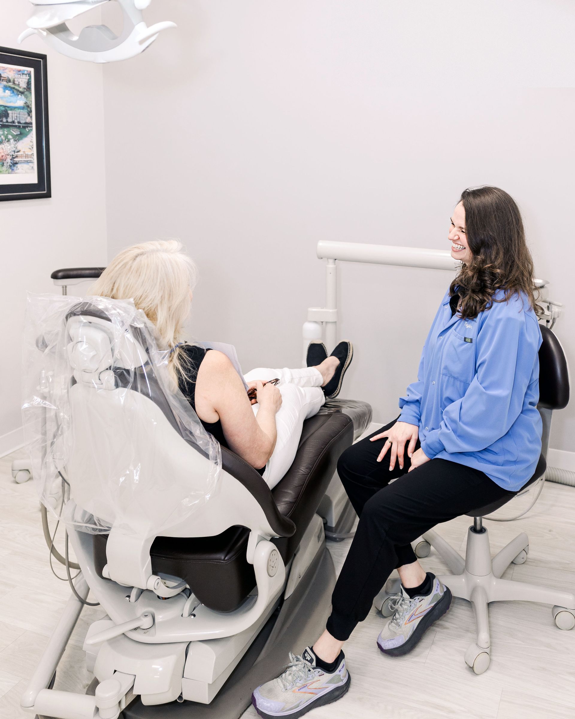 Patient in a dental chair talking with a dentist in a bright clinic.