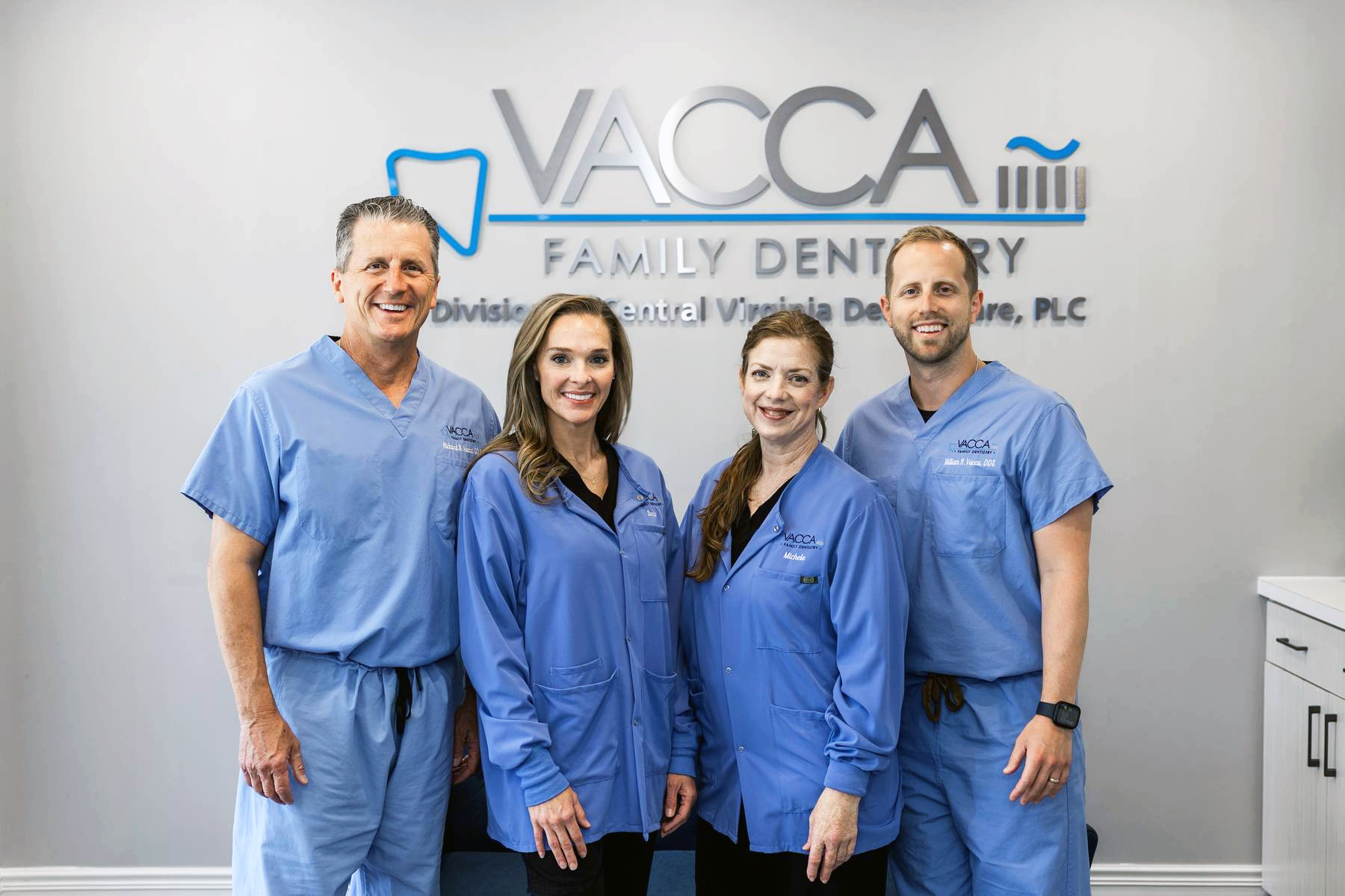 A group of dentists are posing for a picture in front of a dental office.