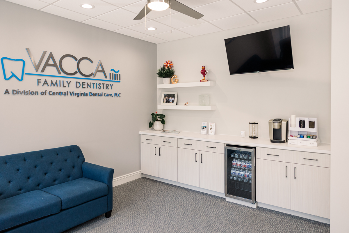 A waiting room with a blue couch and a flat screen tv.