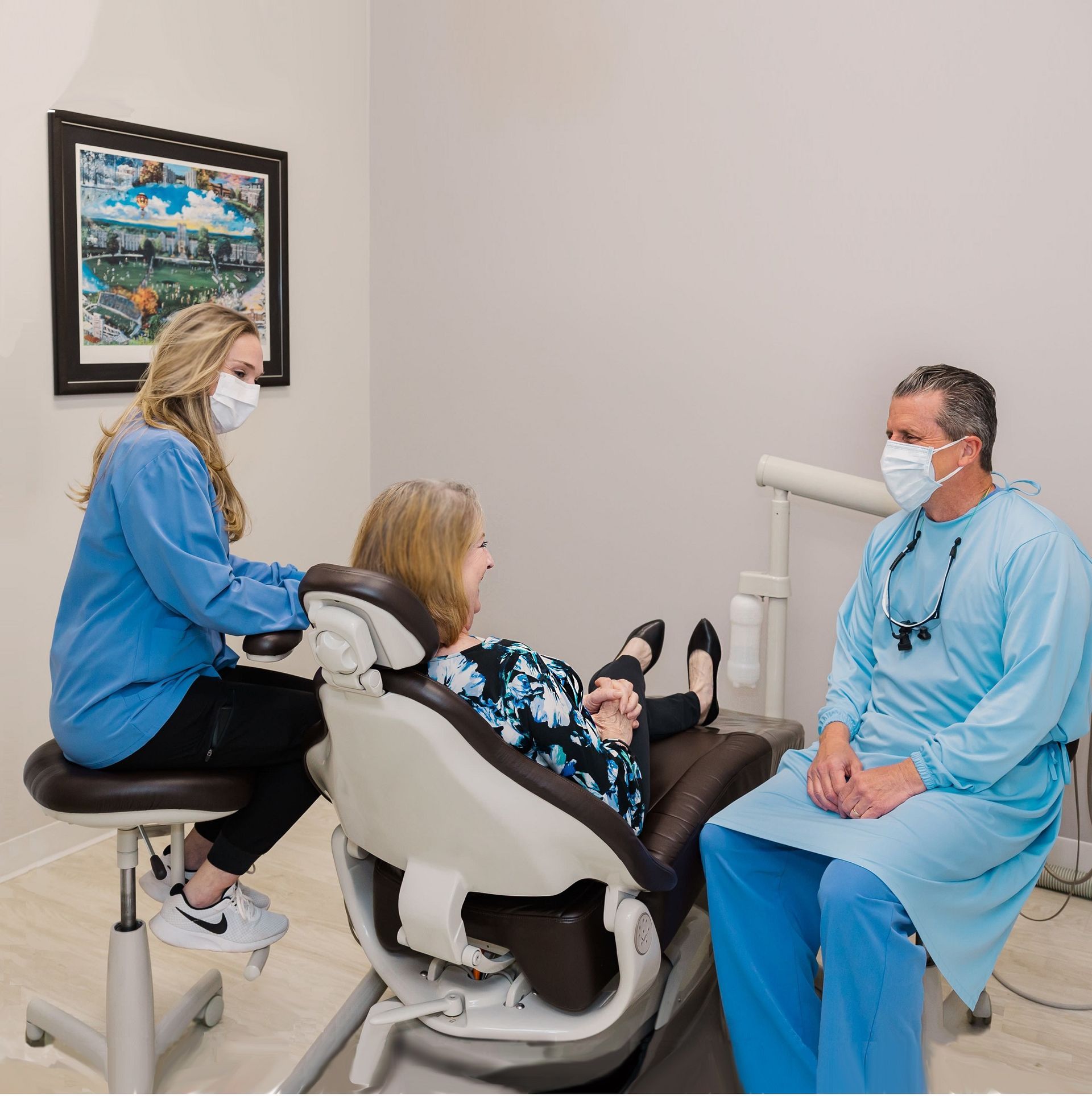 A dentist and assistant wearing masks attend to a patient in a dental office.