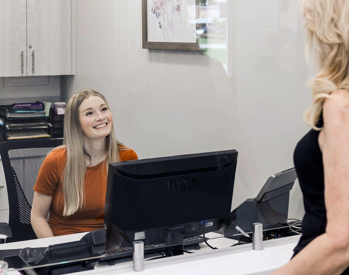 Reception desk with a smiling clerk speaking to a customer in an office lobby