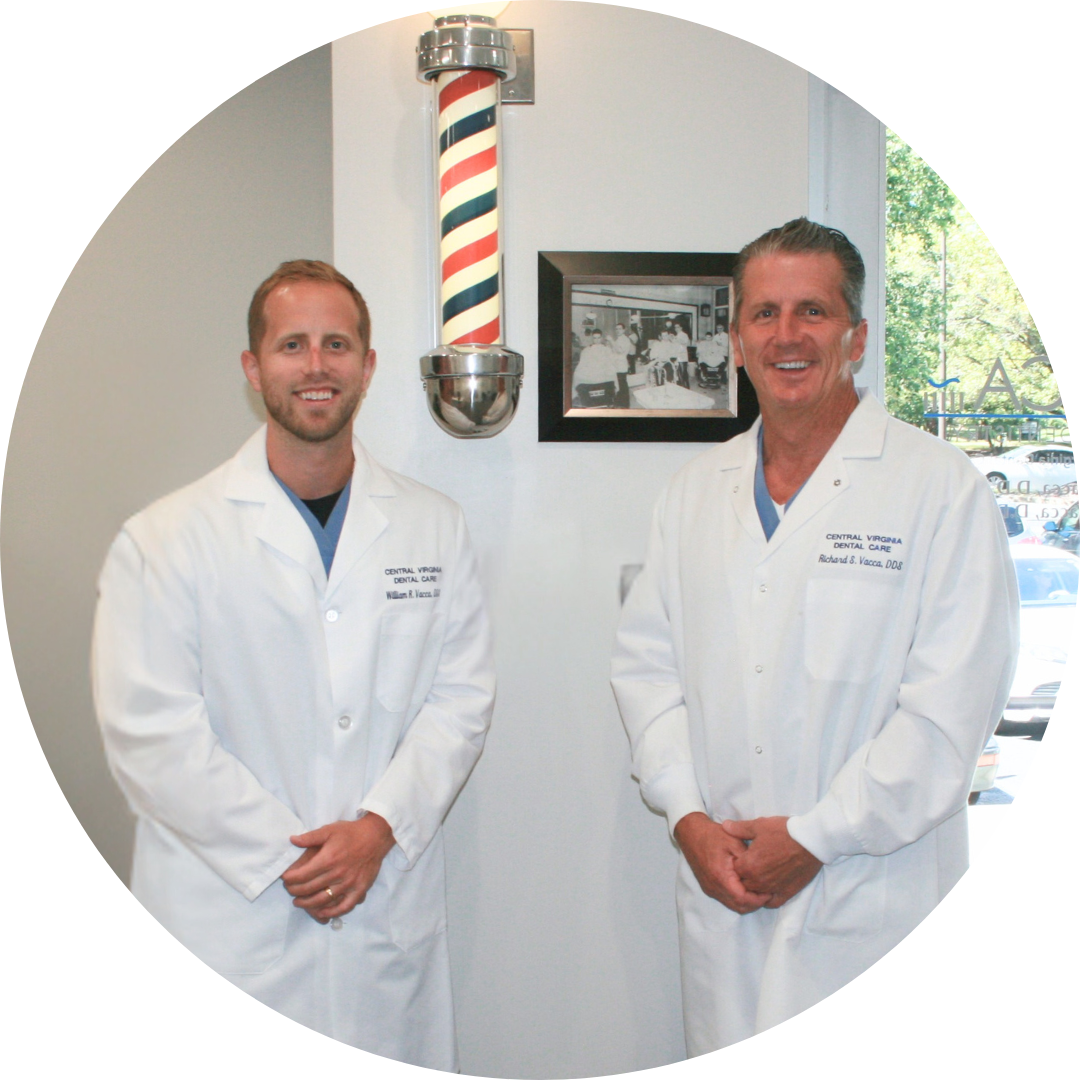 Two men in white coats stand in front of a barber pole