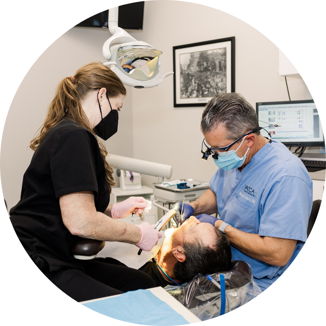 A man is getting his teeth examined by a dentist and a nurse.