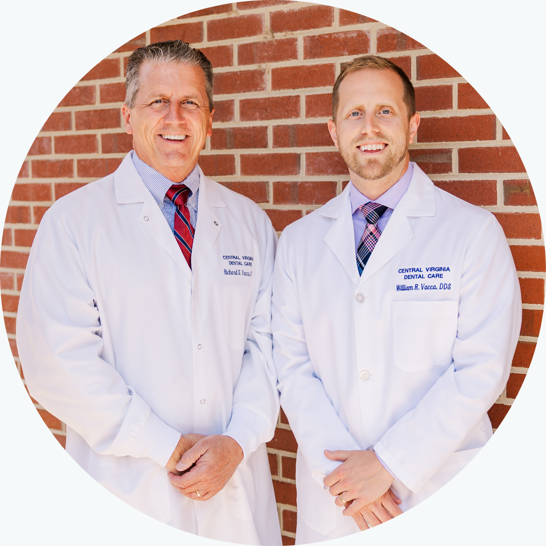 Two doctors are posing for a picture in front of a brick wall