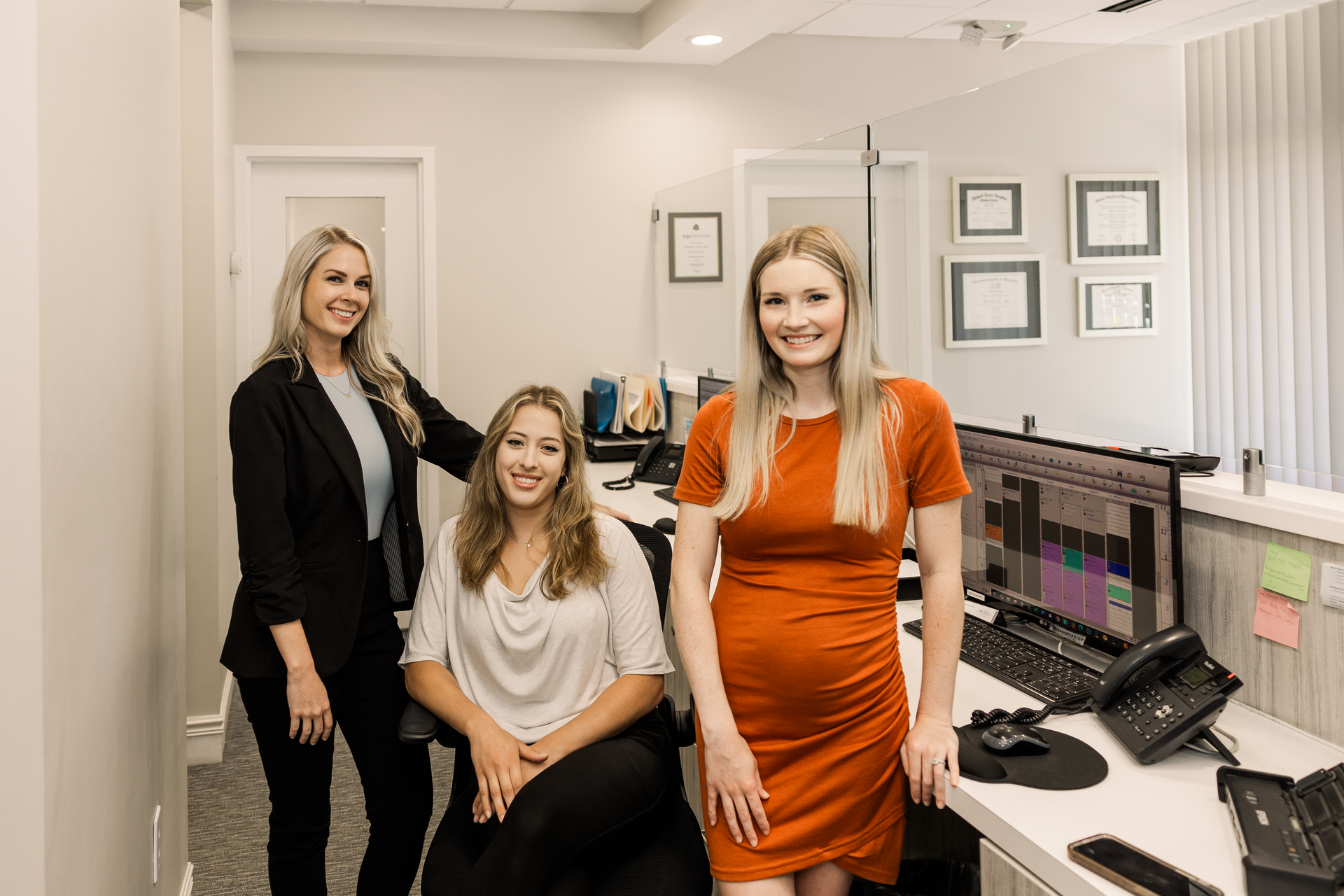 Three women are posing for a picture in an office.