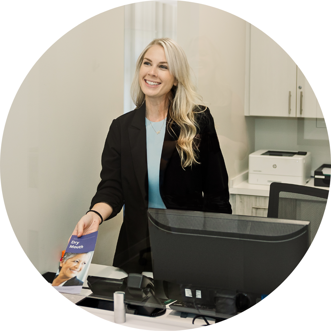 A woman is standing in front of a computer and smiling.