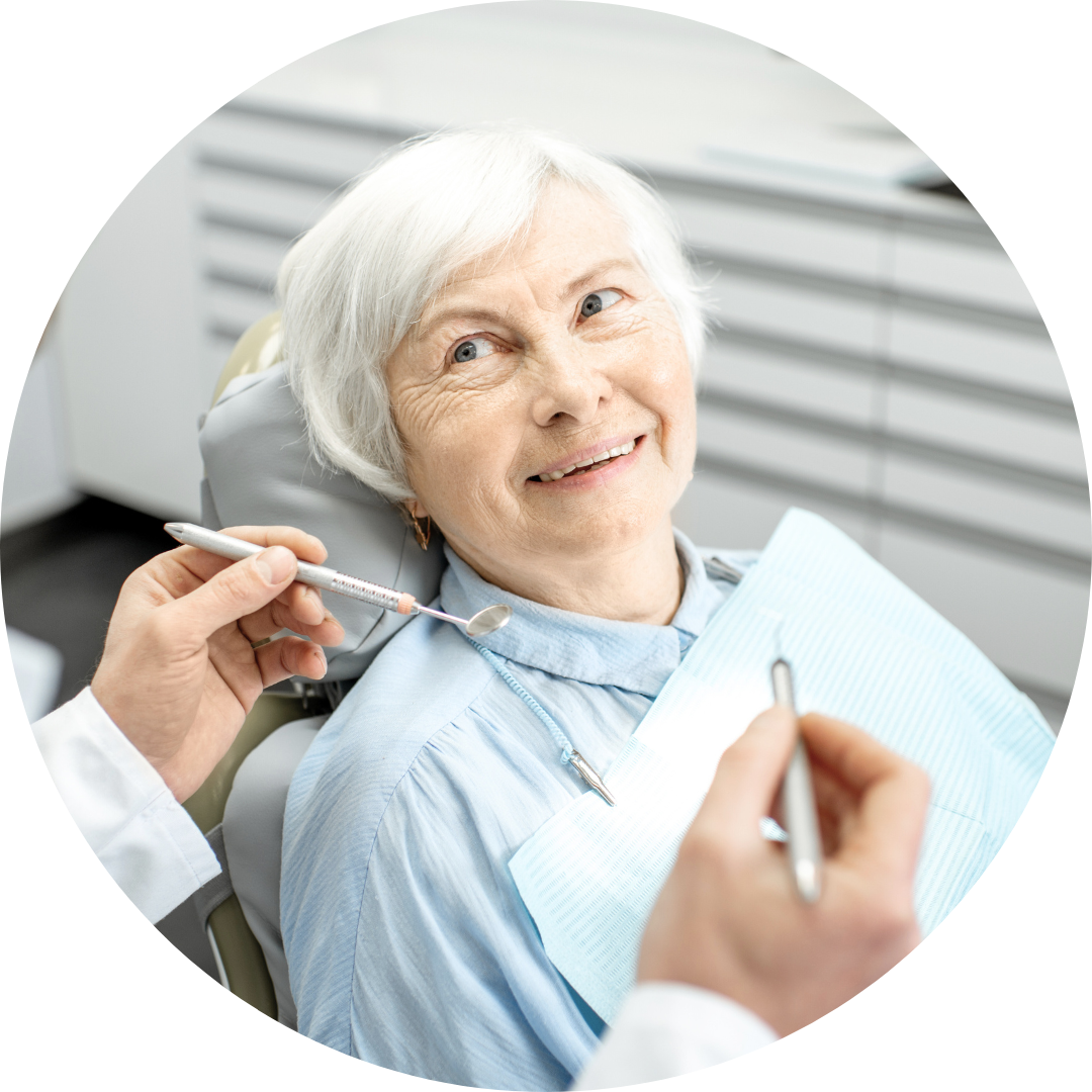 An elderly woman is sitting in a dental chair while a dentist examines her teeth.