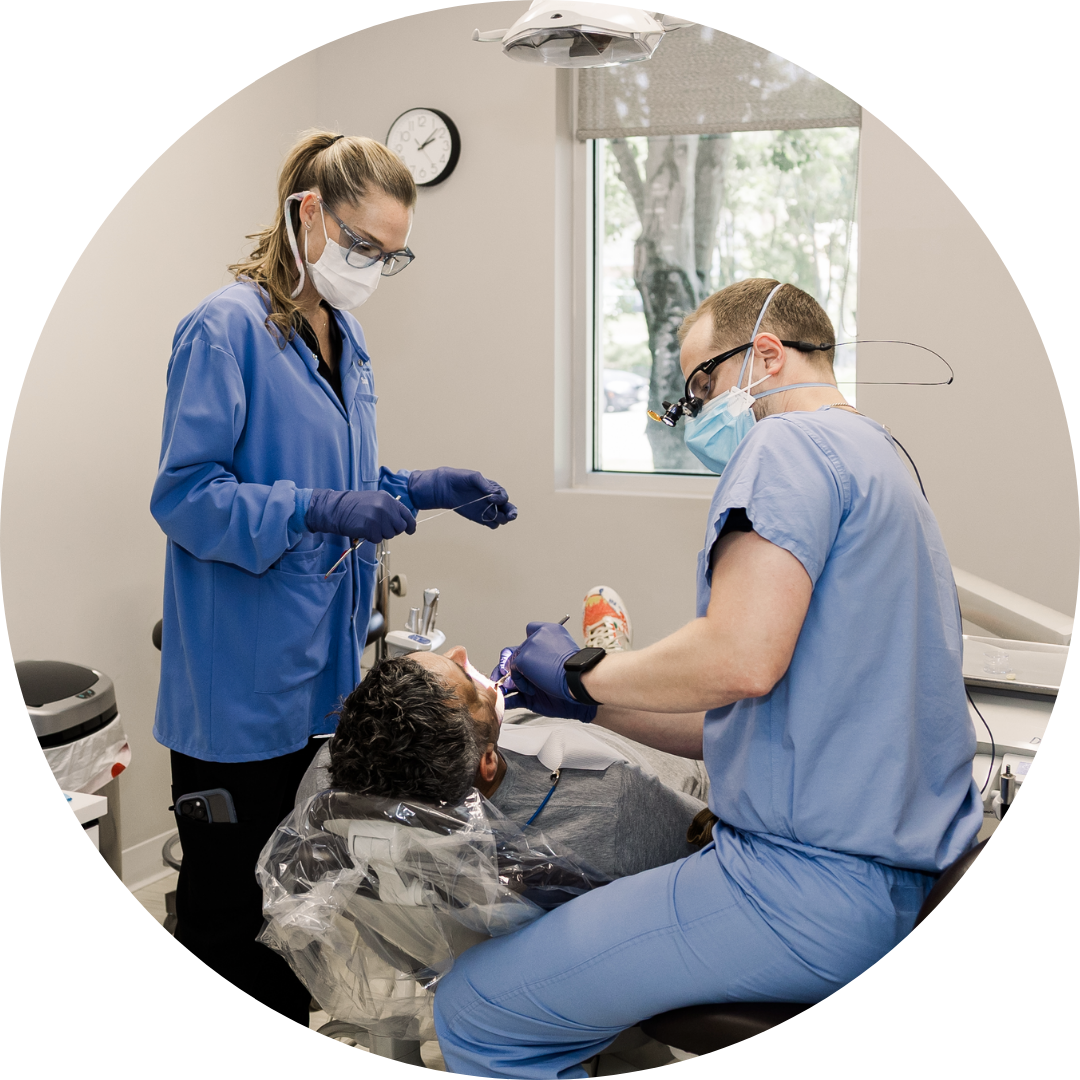 A woman in a floral shirt is looking at her teeth on a screen