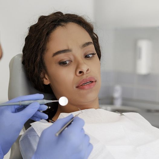 A woman is getting her teeth examined by a dentist