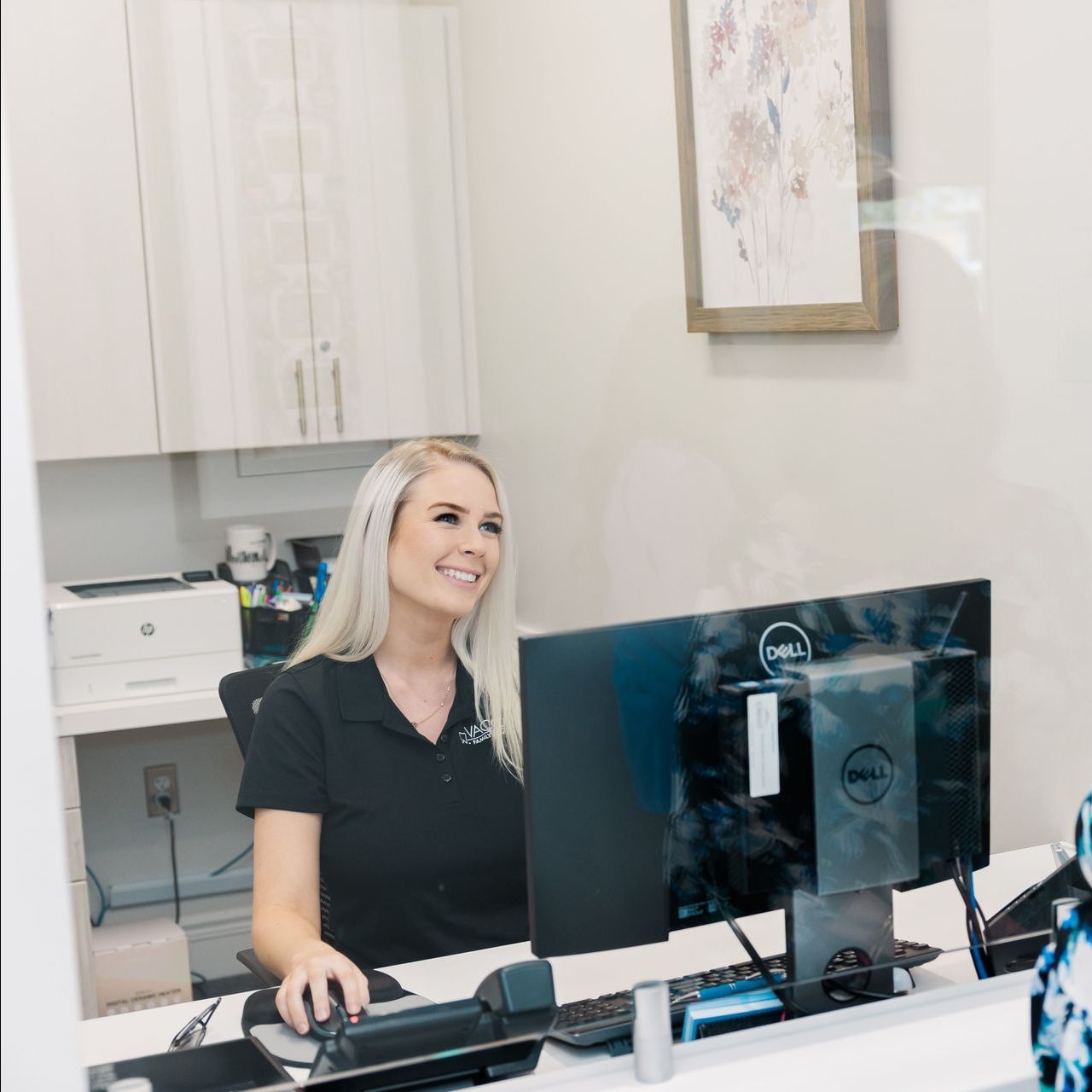 A woman is sitting at a desk in front of a dell computer.