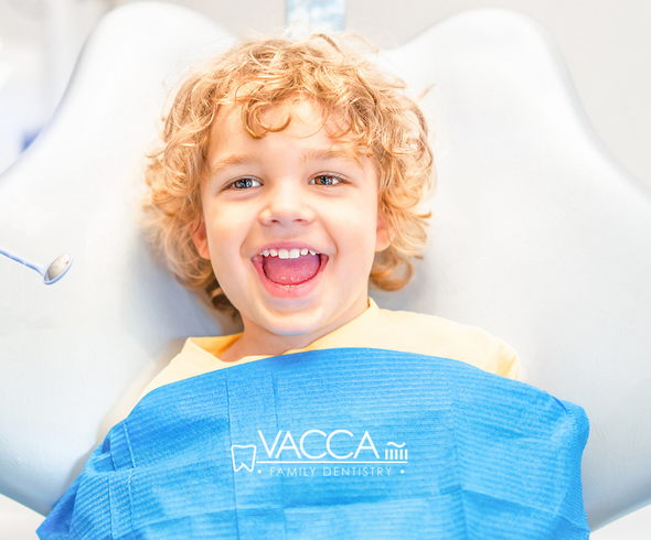 A young boy is smiling while sitting in a dental chair.
