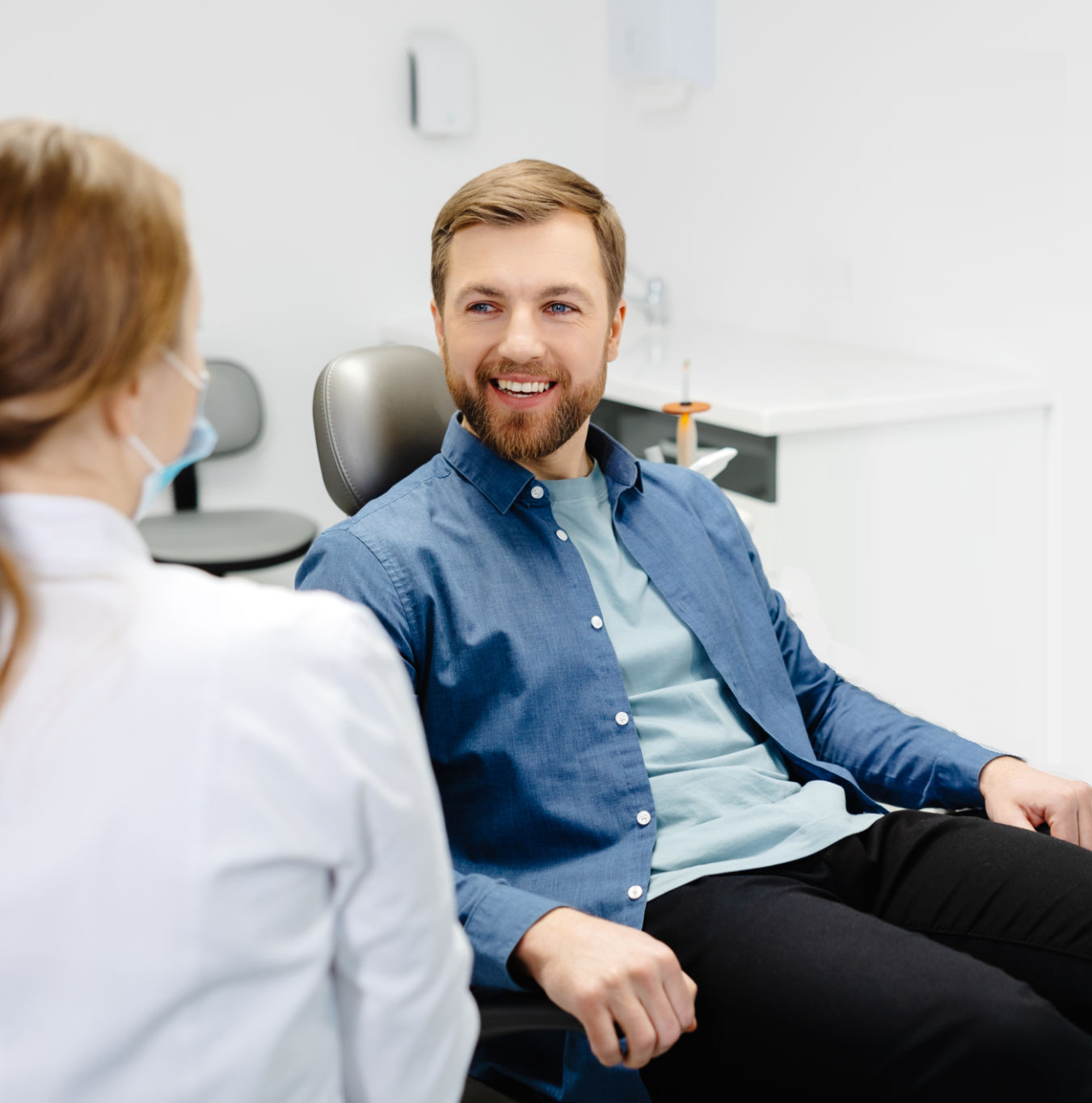 A man is sitting in a dental chair talking to a dentist
