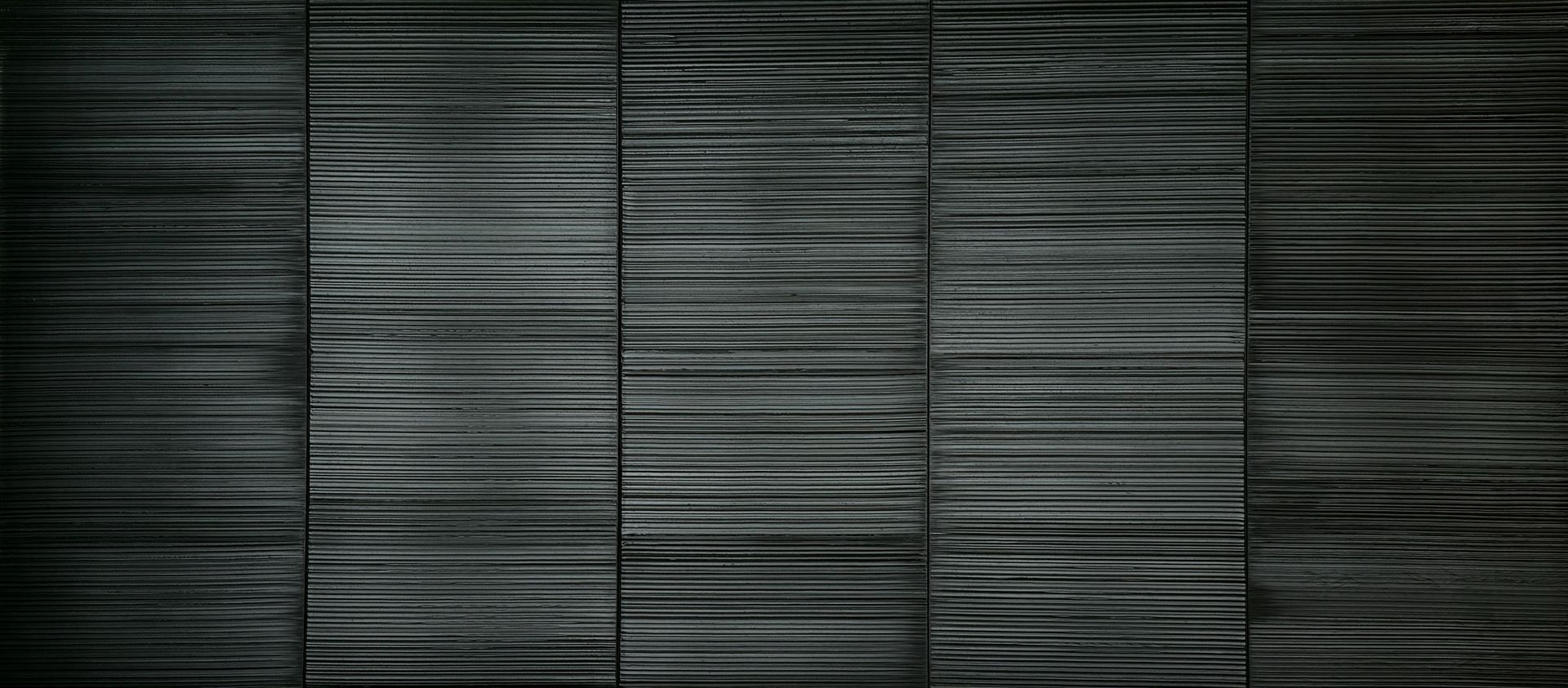 Dark gray wall made of horizontal rectangular panels.