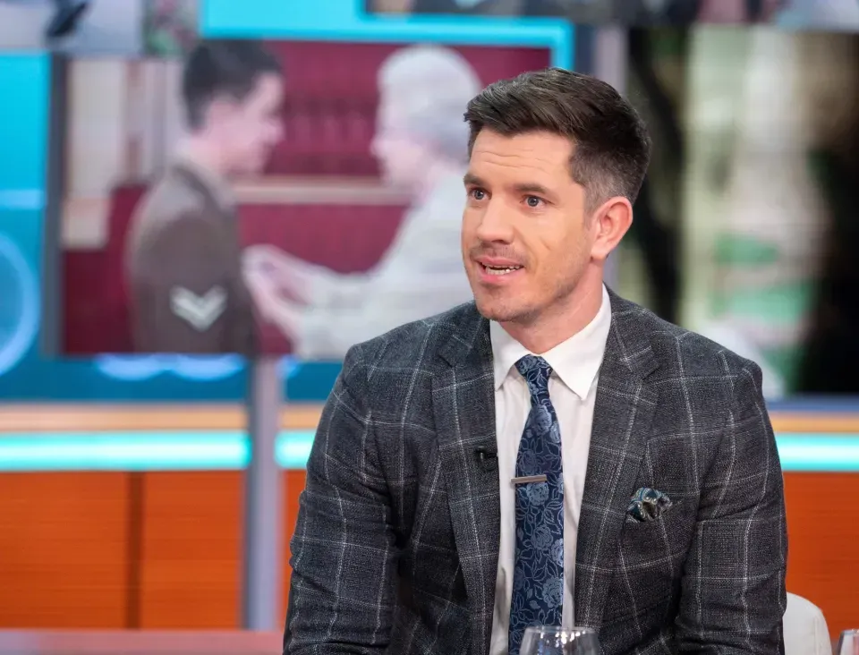 A man in a suit and tie is sitting on a stage.