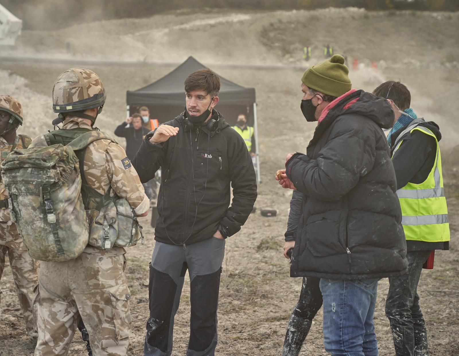 A group of men are standing in a field talking to each other.