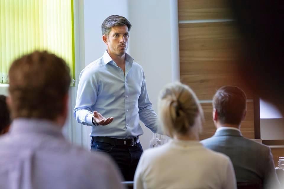 A man is giving a presentation to a group of people in a conference room.