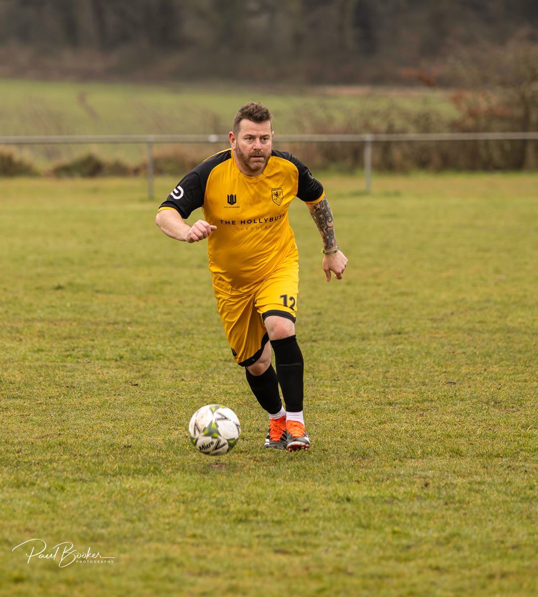 A man in a yellow jersey is playing soccer on a field.