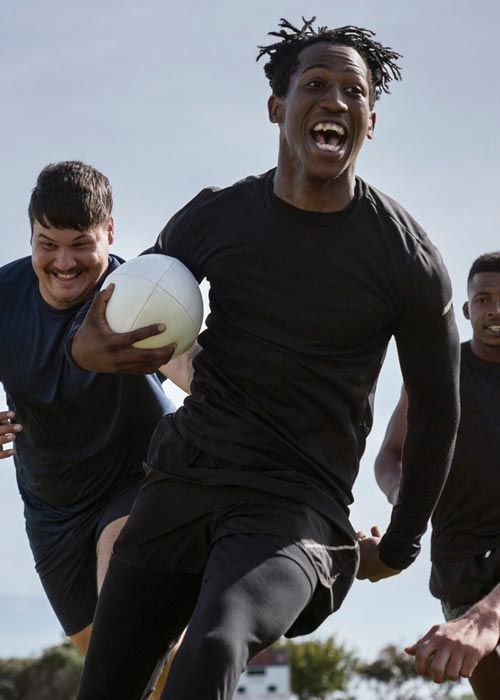 A man in a black shirt is running with a soccer ball