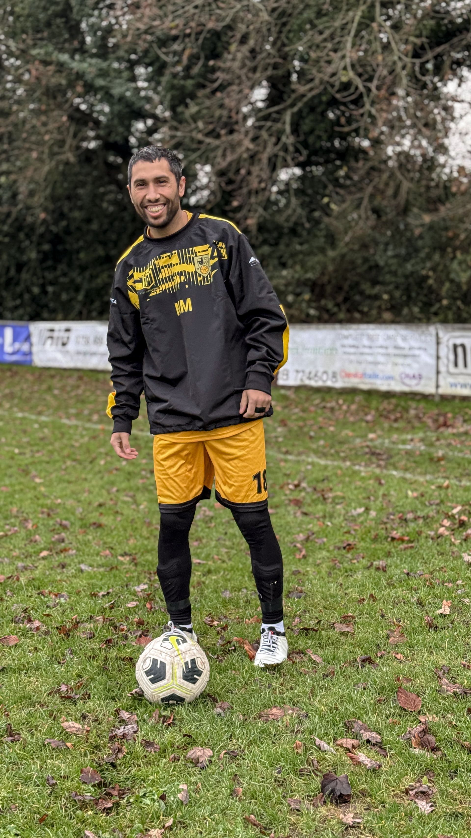 A man is standing on a soccer field with a soccer ball.