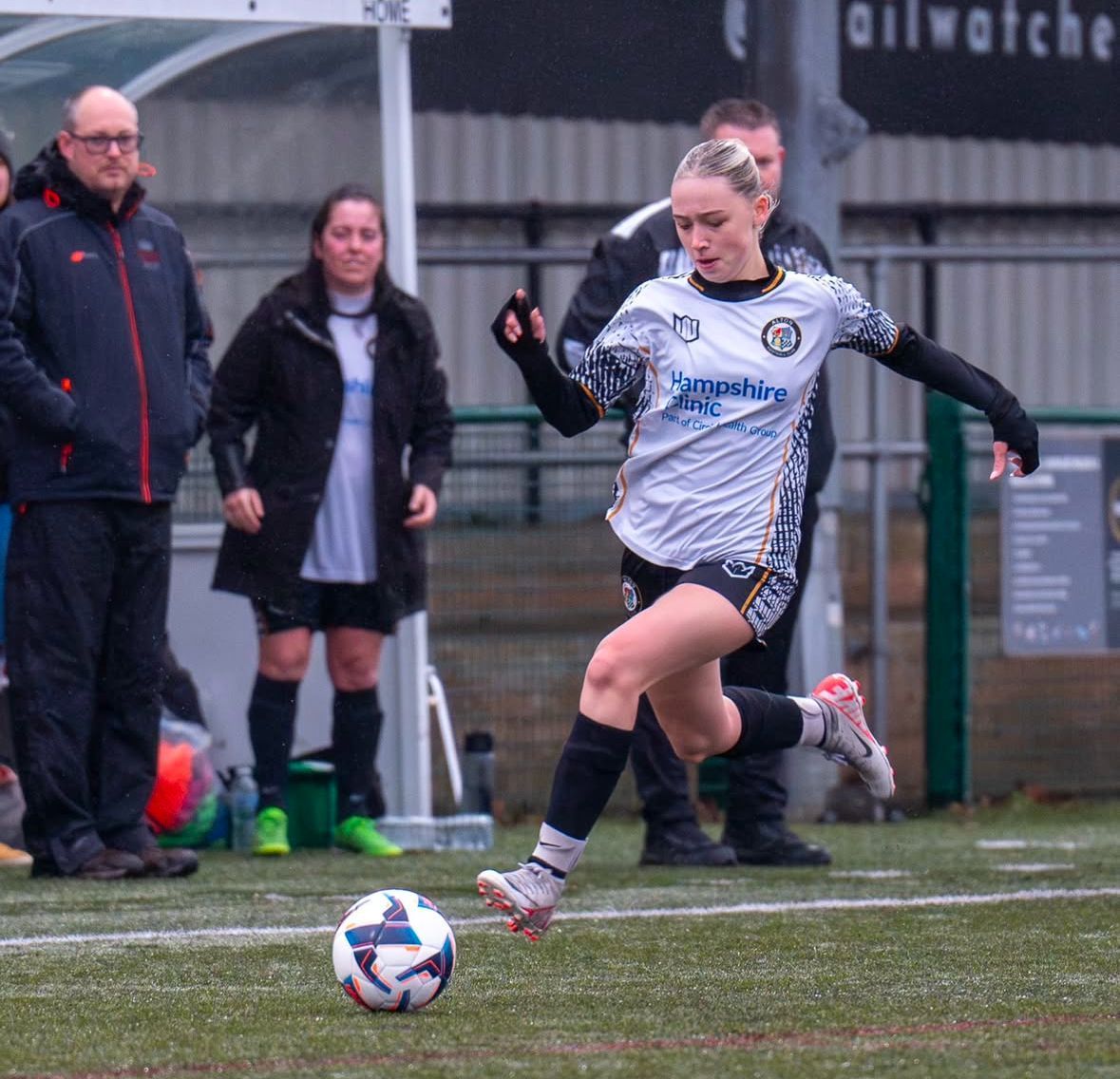 A woman is kicking a soccer ball on a field