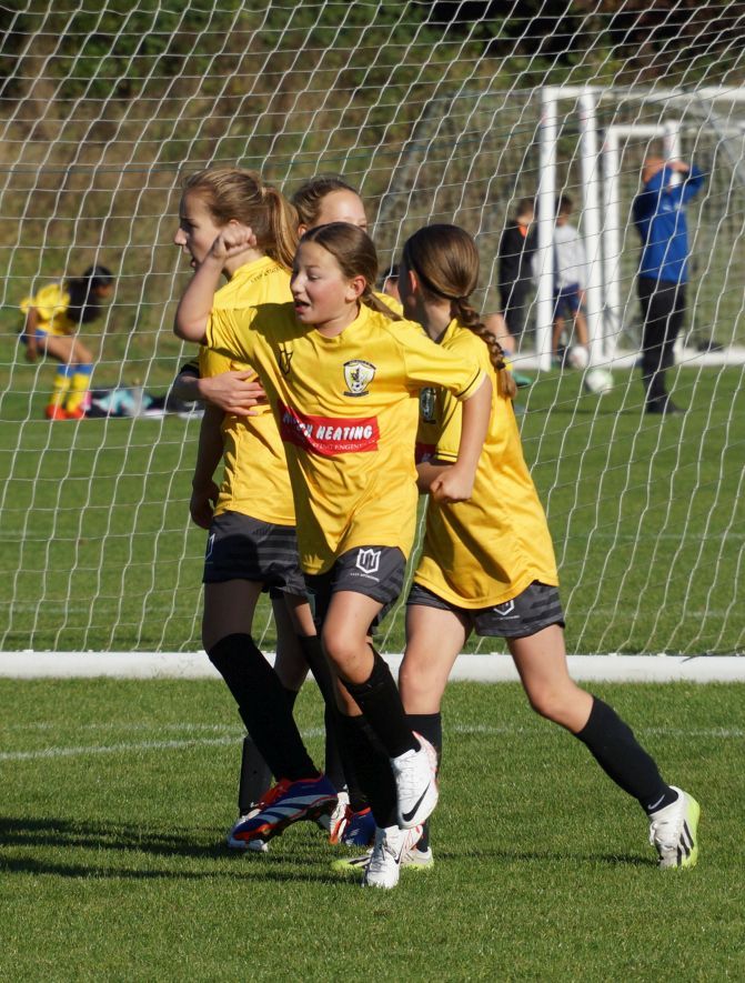 A group of young girls are playing soccer on a field