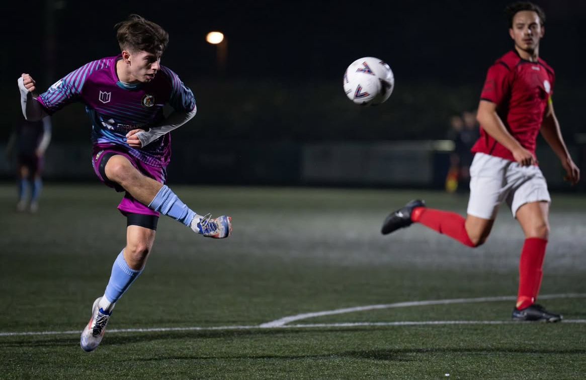 Two soccer players are playing a game of soccer on a field at night.