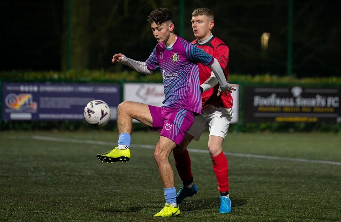Two soccer players are playing a game of soccer on a field.