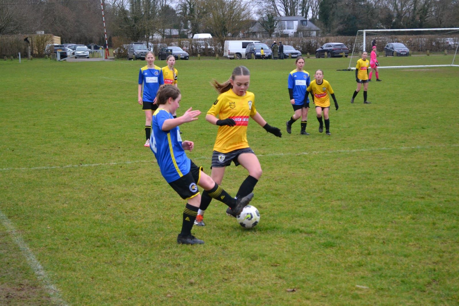 A group of young girls are playing soccer on a field.