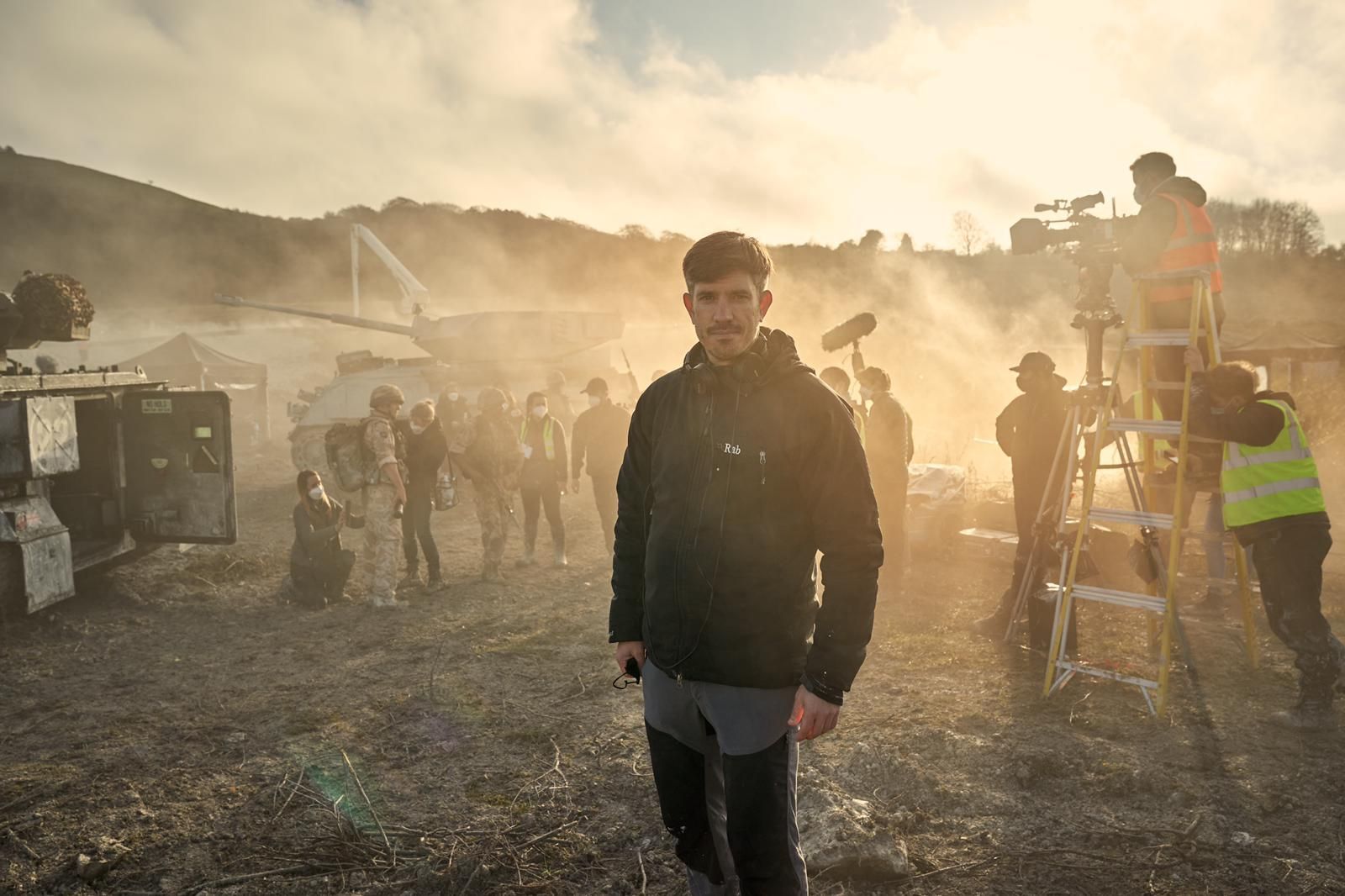 A man is standing in front of a group of people on a film set.