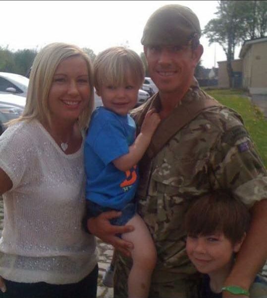 A man in a military uniform holds a little boy in his arms