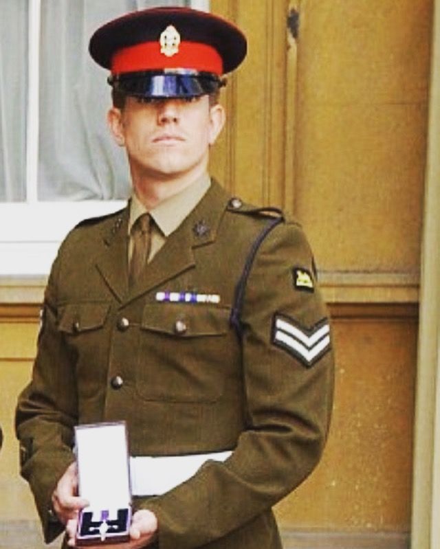 A man in a military uniform is holding a medal