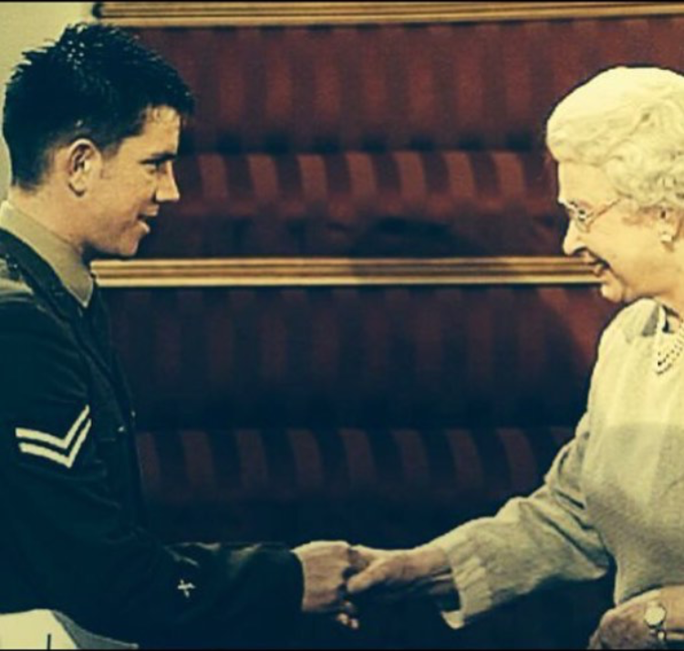 A man in a military uniform shakes hands with queen elizabeth