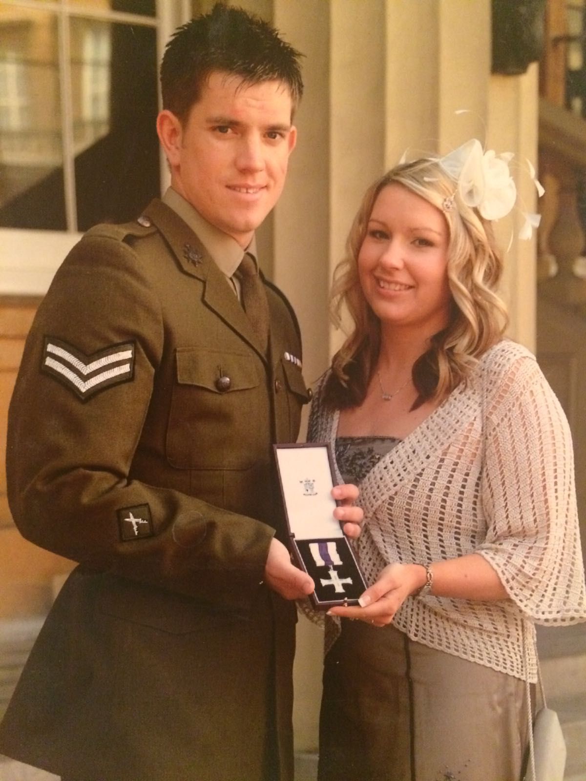 A man in a military uniform is giving a medal to a woman