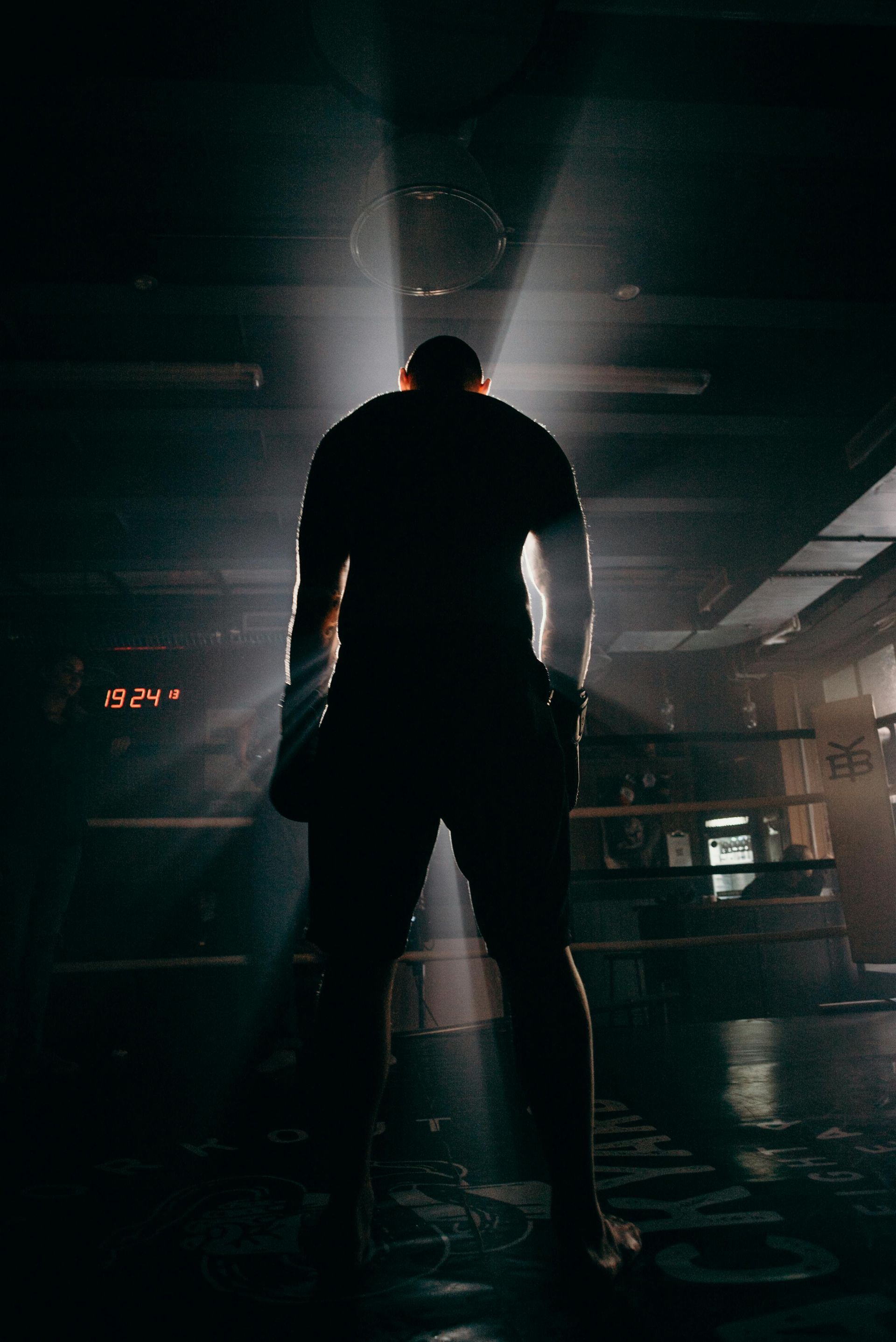 A man is standing in a boxing ring in the dark.